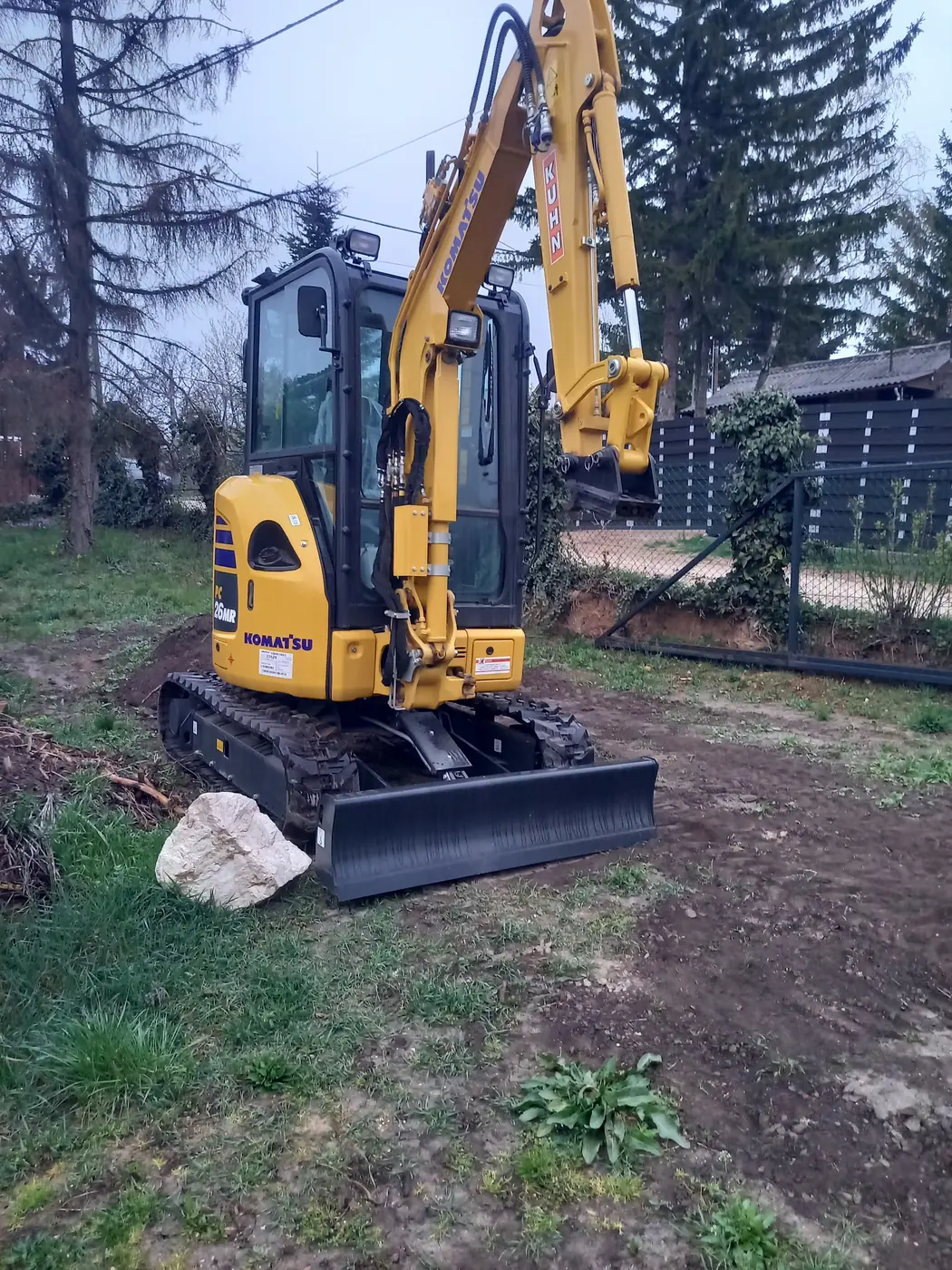 Sárga Komatsu kotró füves telken